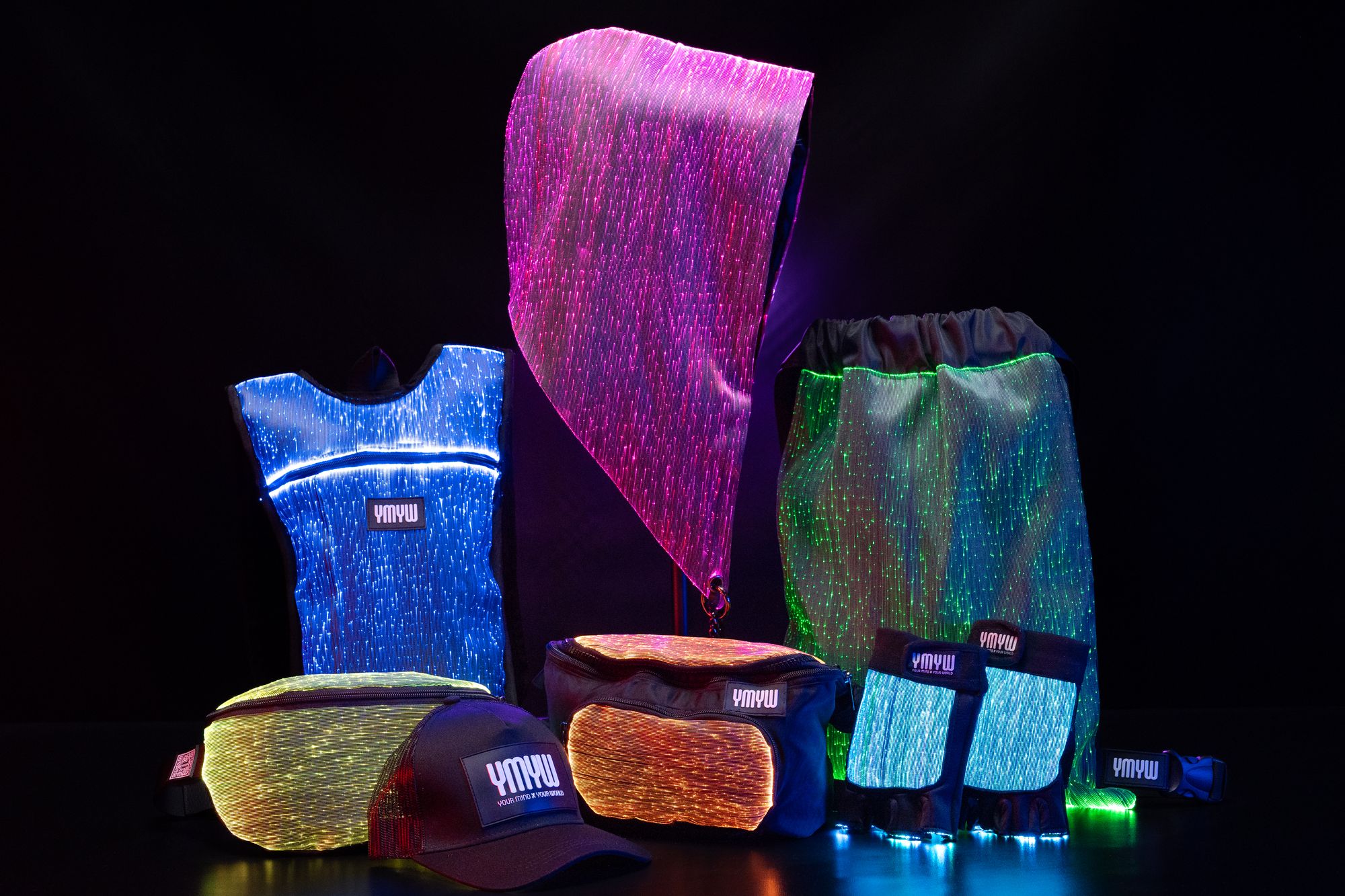 YMYW fiber-optic light-up festival gear collection &mdash; hoods, vests, hydropacks, fanny packs, gloves glowing in the dark