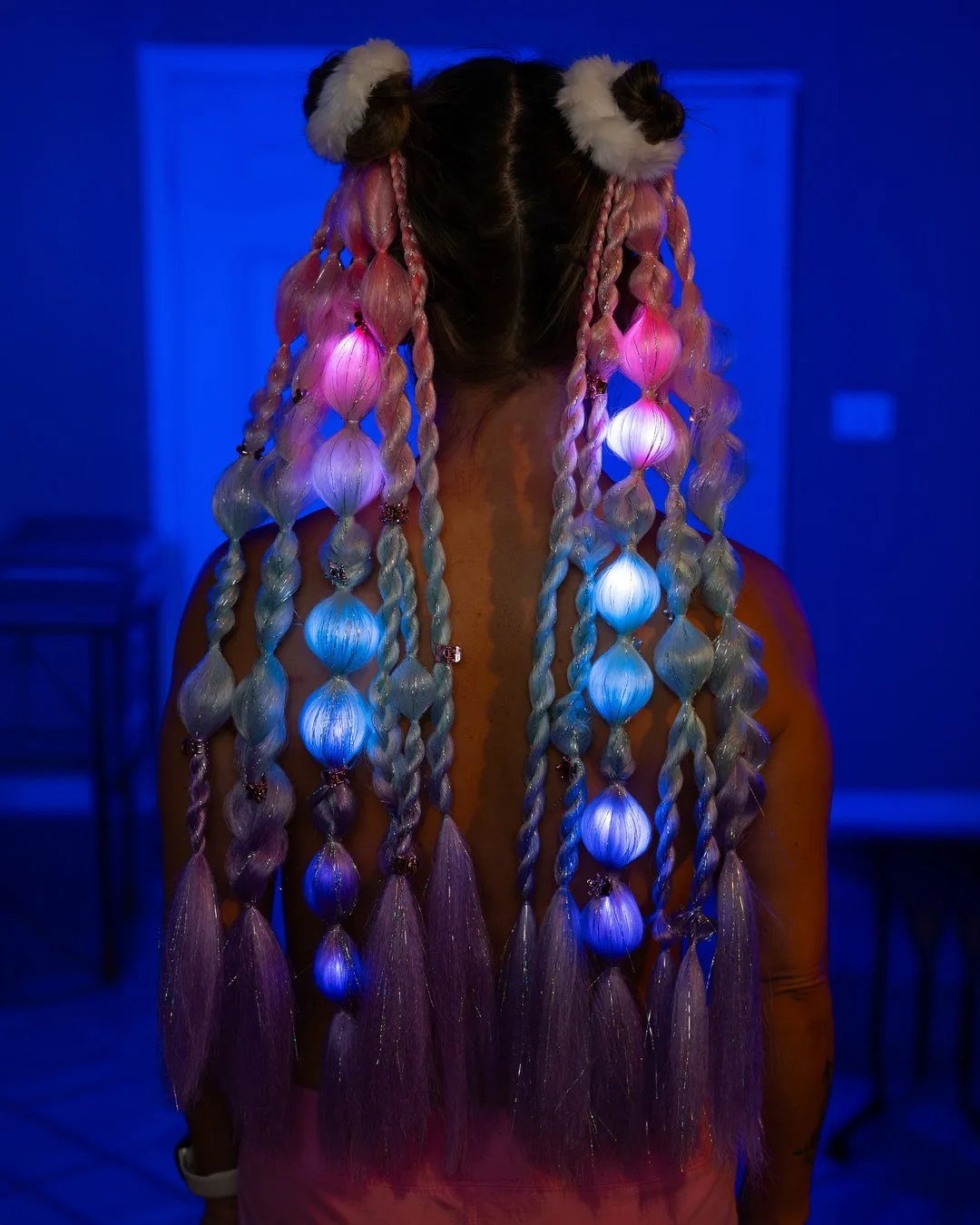 Model wearing extra-long pink and aqua LED fairy hair extensions glowing after dark