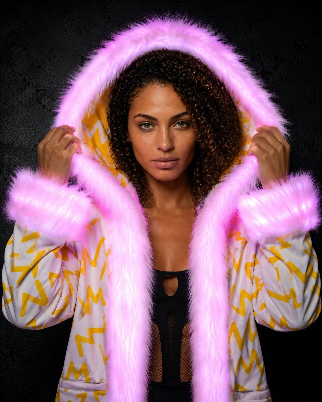 Woman in a yellow and white LED fur coat with pink glowing hood